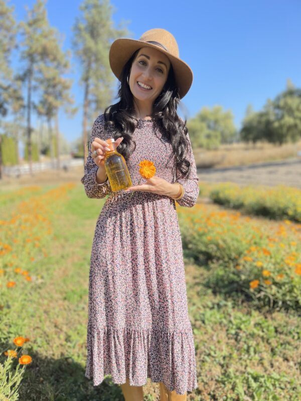 HUNA Founder Heather holding Botanical Body Nectar in the Huna Gardens